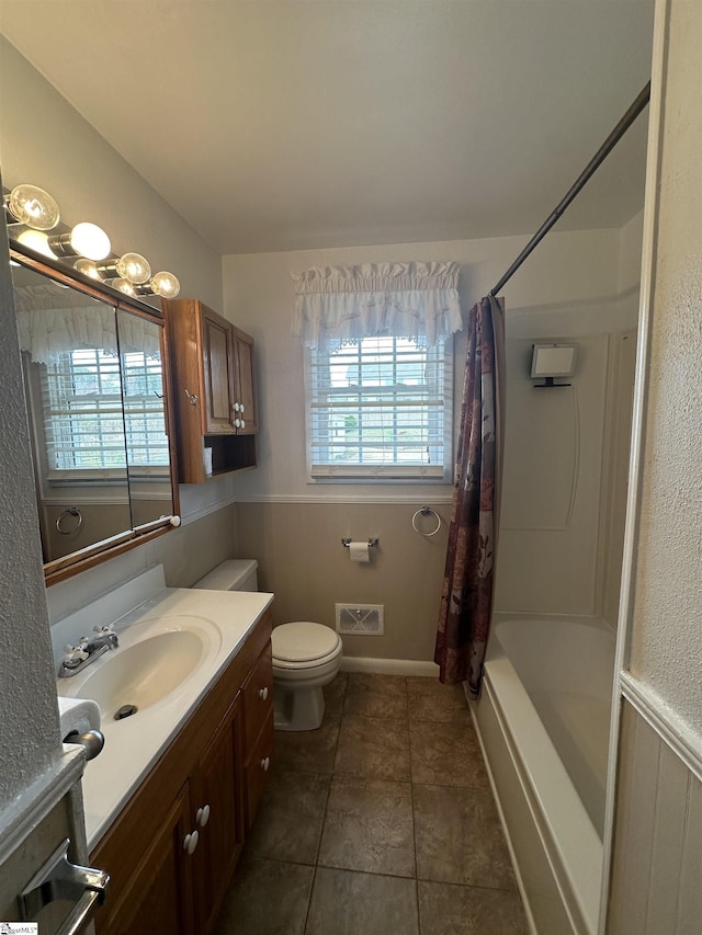 bathroom featuring toilet, plenty of natural light, shower / bath combo with shower curtain, and vanity