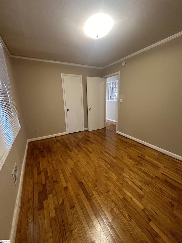 unfurnished room with baseboards, wood finished floors, and crown molding