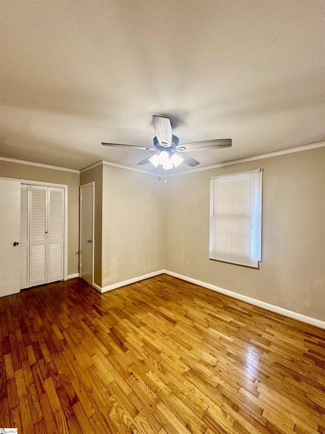 unfurnished bedroom featuring baseboards, a ceiling fan, crown molding, and wood-type flooring
