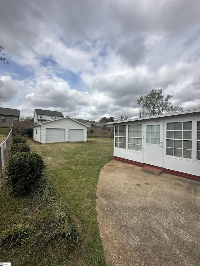 view of yard with a garage, fence, and an outbuilding