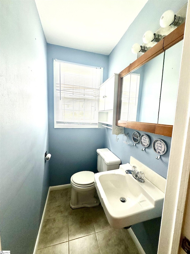 bathroom with toilet, a sink, baseboards, and tile patterned flooring