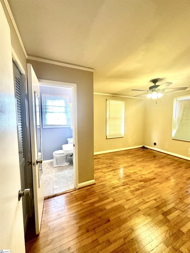 empty room featuring baseboards, ornamental molding, ceiling fan, and light wood finished floors