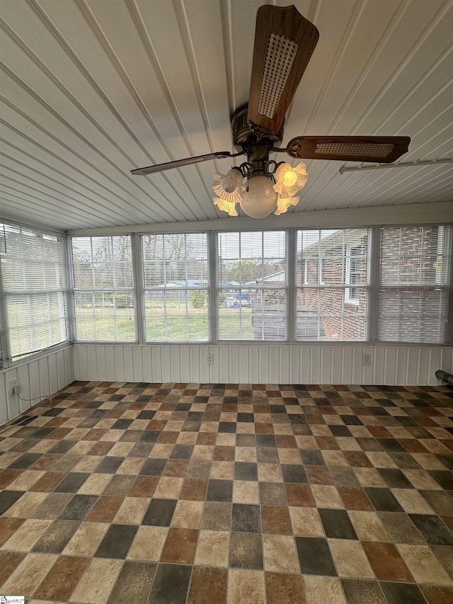 unfurnished sunroom featuring a ceiling fan and plenty of natural light