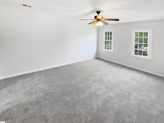 empty room featuring carpet flooring, a ceiling fan, baseboards, and visible vents