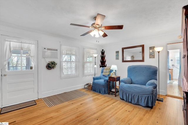 foyer with ceiling fan, baseboards, light wood-style floors, an AC wall unit, and ornamental molding