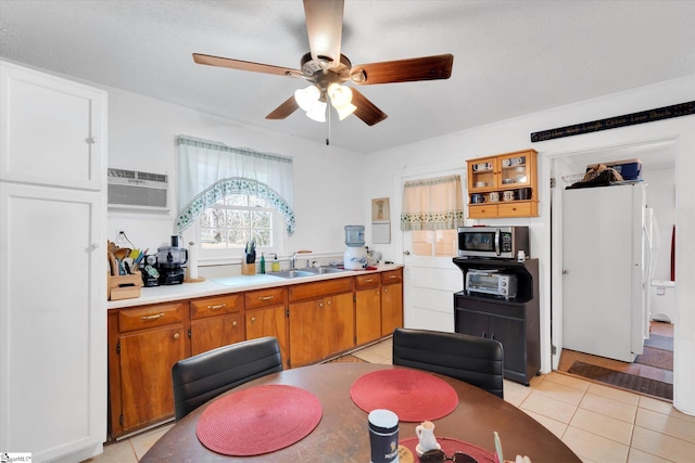 kitchen with a wall mounted air conditioner, light tile patterned flooring, ceiling fan, stainless steel microwave, and a sink