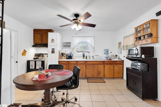kitchen featuring light countertops, ceiling fan, stainless steel microwave, brown cabinets, and freestanding refrigerator