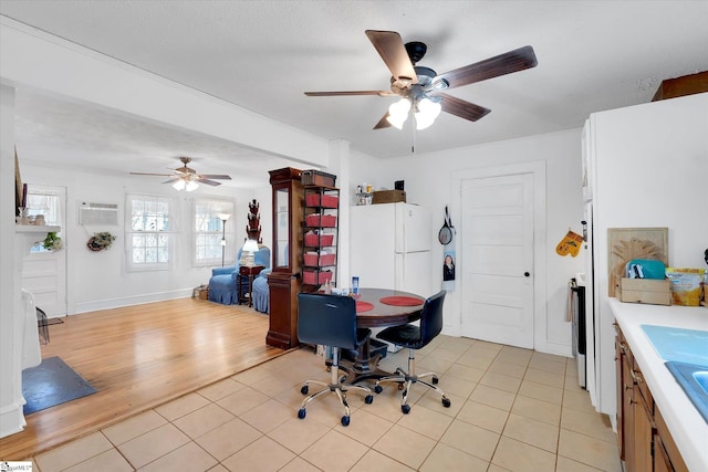 interior space with ceiling fan, a wall unit AC, and light tile patterned floors