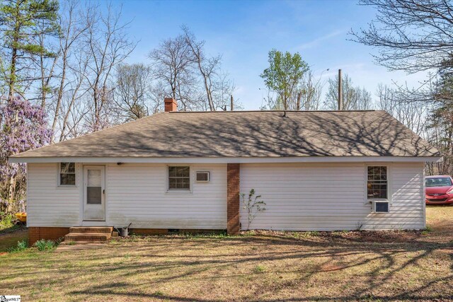 back of property featuring a shingled roof, a lawn, a chimney, and entry steps