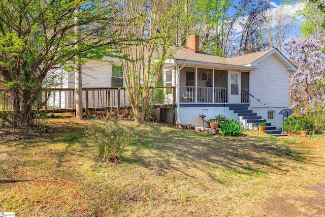 view of front facade featuring a sunroom, a chimney, stairs, a front yard, and a shingled roof