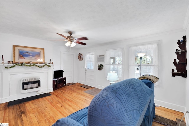 living room with light wood-style flooring, baseboards, a ceiling fan, heating unit, and an AC wall unit