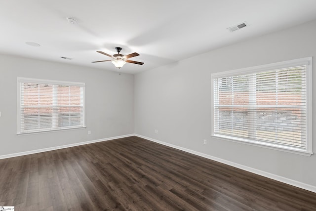 spare room featuring a ceiling fan, dark wood-style flooring, baseboards, and visible vents