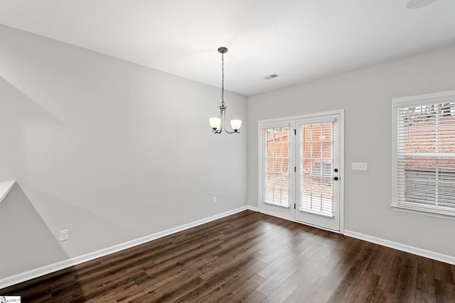 unfurnished dining area with baseboards, visible vents, dark wood-type flooring, and an inviting chandelier