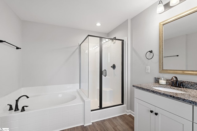 full bathroom featuring a shower stall, wood finished floors, vanity, and a garden tub