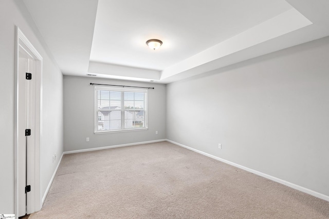 unfurnished bedroom with a tray ceiling, baseboards, and light colored carpet