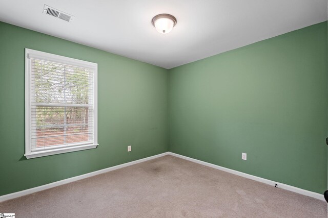 carpeted spare room featuring baseboards and visible vents