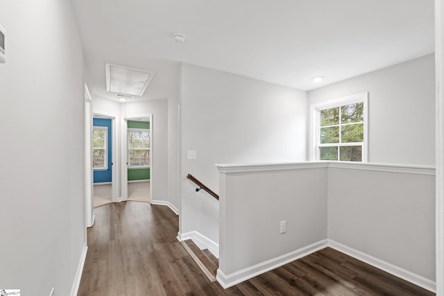 hallway with attic access, baseboards, an upstairs landing, and dark wood-style flooring