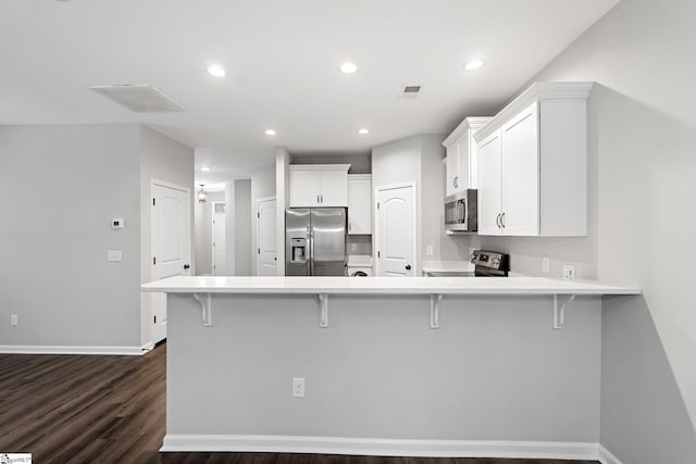 kitchen with visible vents, stainless steel appliances, a kitchen breakfast bar, and a peninsula