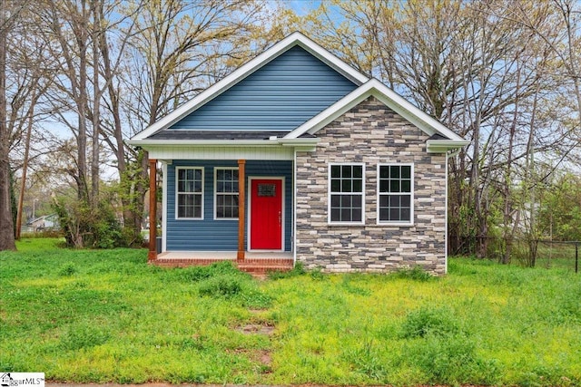 view of front of house with stone siding, a front lawn, and a porch