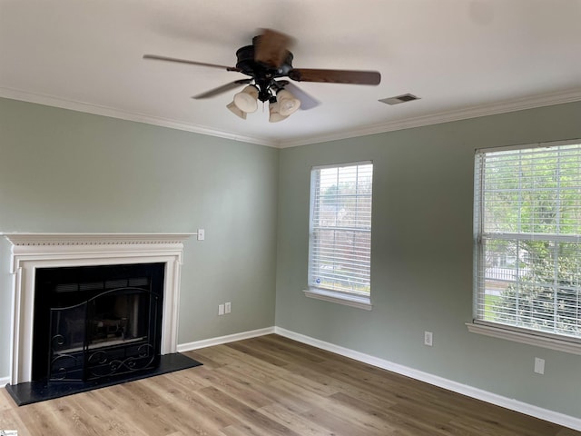 unfurnished living room with ornamental molding, baseboards, ceiling fan, visible vents, and wood finished floors