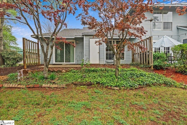 rear view of house featuring fence and a yard
