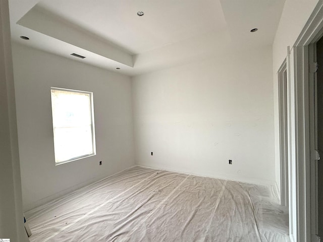 empty room with a raised ceiling and visible vents