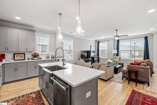 kitchen with light countertops, crown molding, dishwasher, a sink, and gray cabinetry