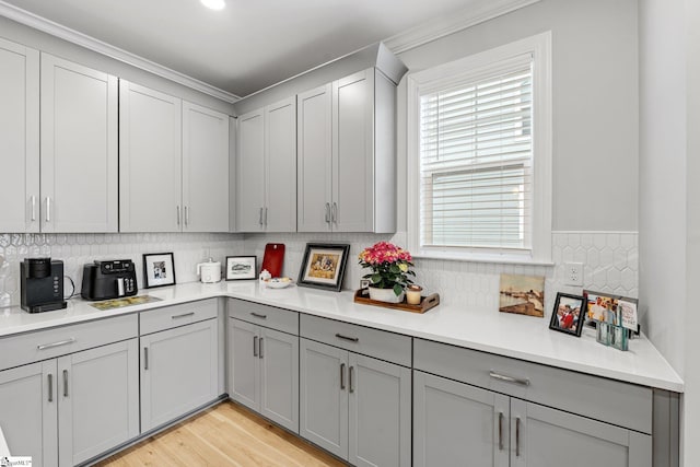 kitchen featuring gray cabinetry, light countertops, backsplash, and light wood-style floors