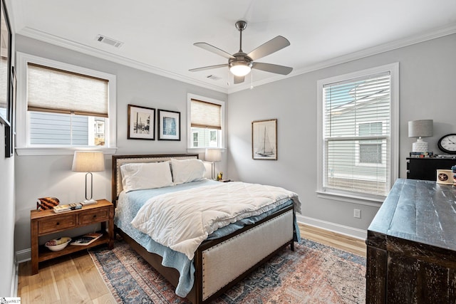 bedroom featuring baseboards, light wood-style flooring, visible vents, and crown molding