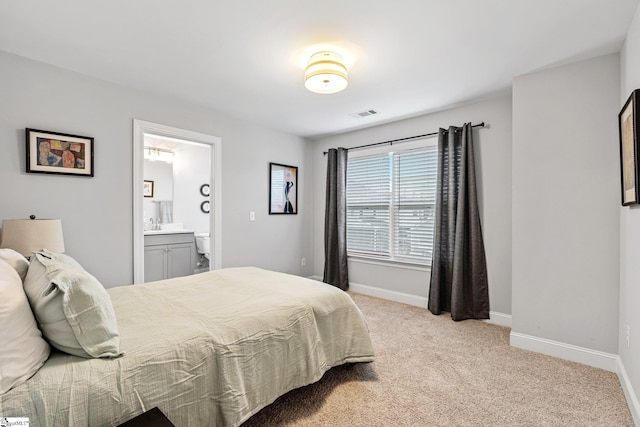 bedroom with baseboards, connected bathroom, visible vents, and light carpet