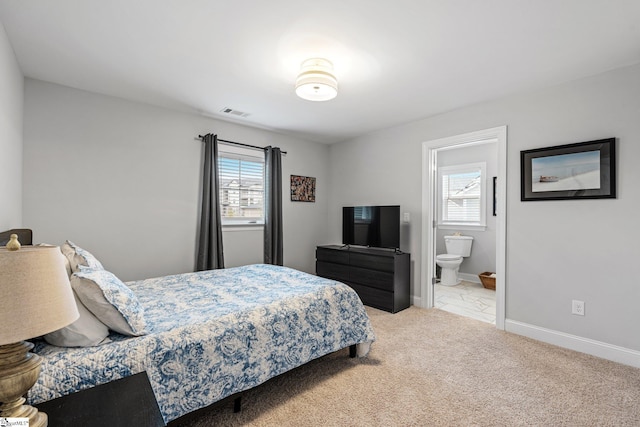 carpeted bedroom with ensuite bathroom, baseboards, multiple windows, and visible vents