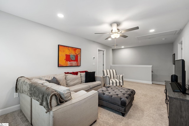living room with baseboards, ceiling fan, attic access, and light colored carpet