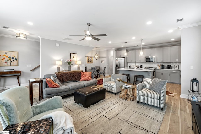 living area with visible vents, ceiling fan, ornamental molding, recessed lighting, and light wood-style floors