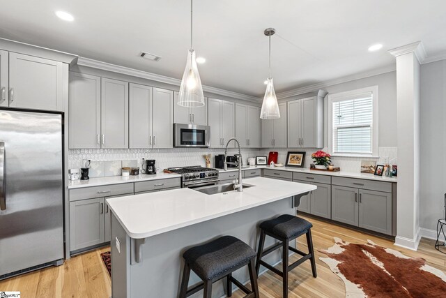 kitchen with gray cabinets, crown molding, a kitchen breakfast bar, appliances with stainless steel finishes, and visible vents