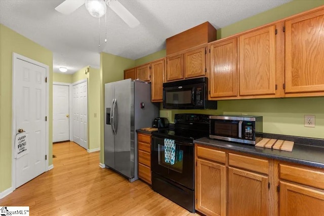 kitchen featuring light wood-type flooring, a textured ceiling, dark countertops, a ceiling fan, and black appliances