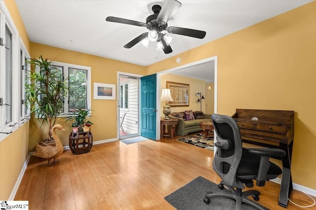 office with baseboards, light wood-type flooring, and a ceiling fan