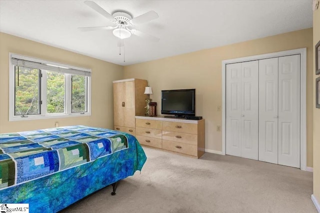 bedroom with baseboards, a closet, a ceiling fan, and light colored carpet