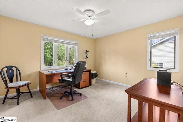 office space featuring a ceiling fan, light carpet, and baseboards