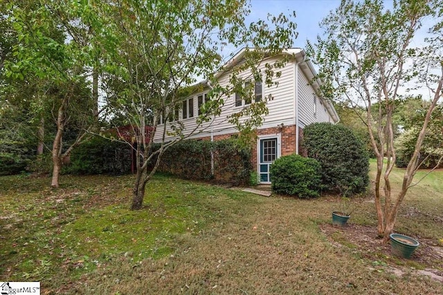 view of home's exterior featuring a lawn and brick siding