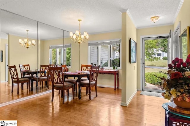 dining space featuring an inviting chandelier, ornamental molding, baseboards, a textured ceiling, and light wood finished floors
