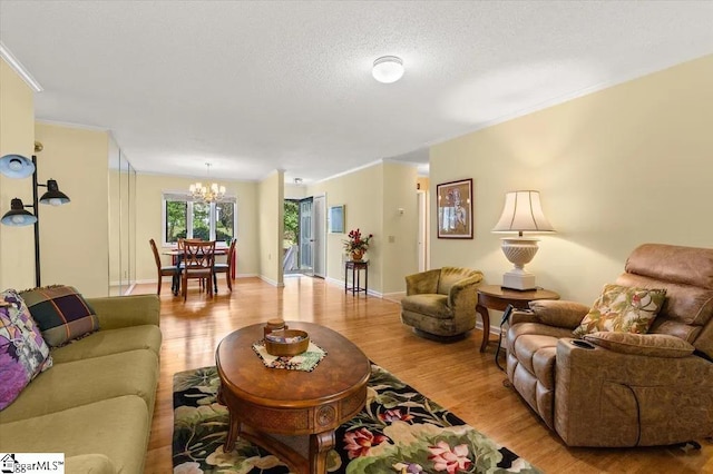 living room featuring baseboards, a textured ceiling, an inviting chandelier, and light wood-style floors