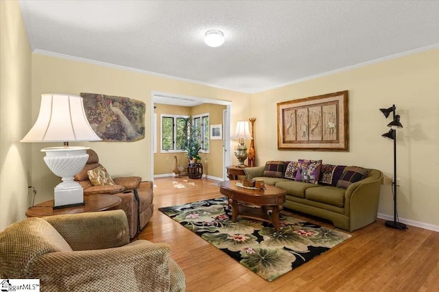 living area featuring baseboards, a textured ceiling, wood finished floors, and crown molding