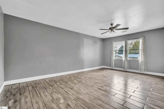 empty room with baseboards, visible vents, ceiling fan, and wood finished floors