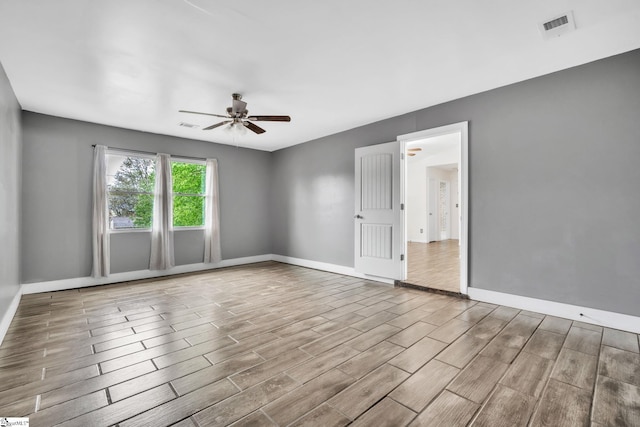 spare room with baseboards, visible vents, wood finished floors, and ceiling fan