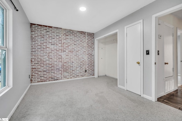 unfurnished bedroom with baseboards, carpet floors, and brick wall