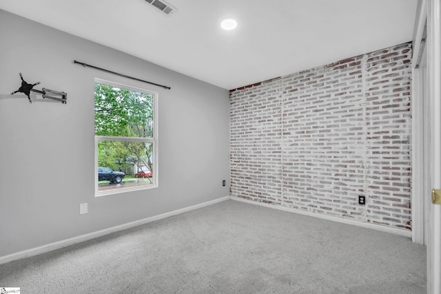 carpeted empty room with baseboards, visible vents, and brick wall