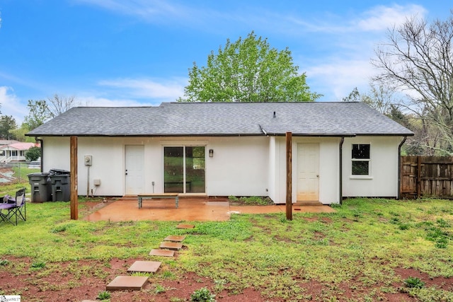 back of property with a lawn, a shingled roof, fence, and a patio
