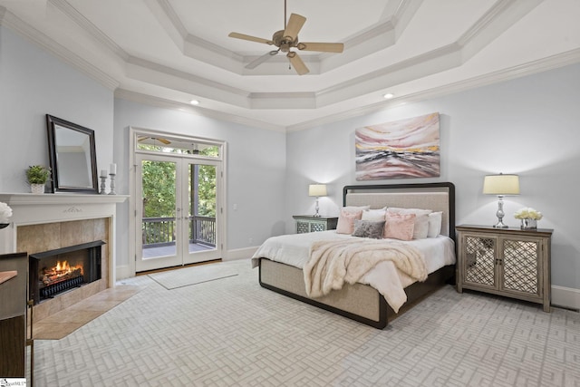 bedroom featuring crown molding, baseboards, a tiled fireplace, access to exterior, and a tray ceiling