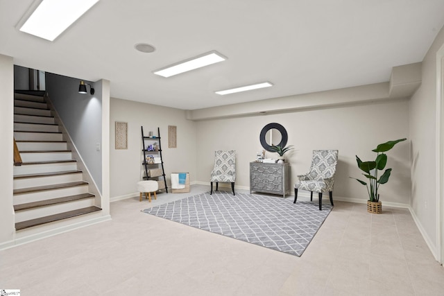 living area featuring baseboards and stairway