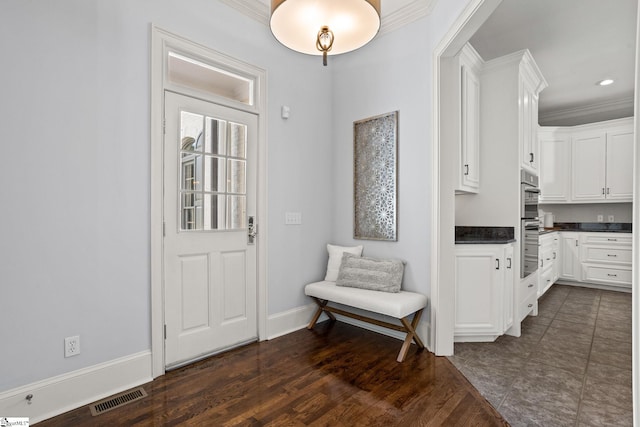 foyer with ornamental molding, dark wood-type flooring, baseboards, and visible vents
